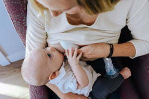 Child breastfeeding while massager is used as a clogged milk duct treatment