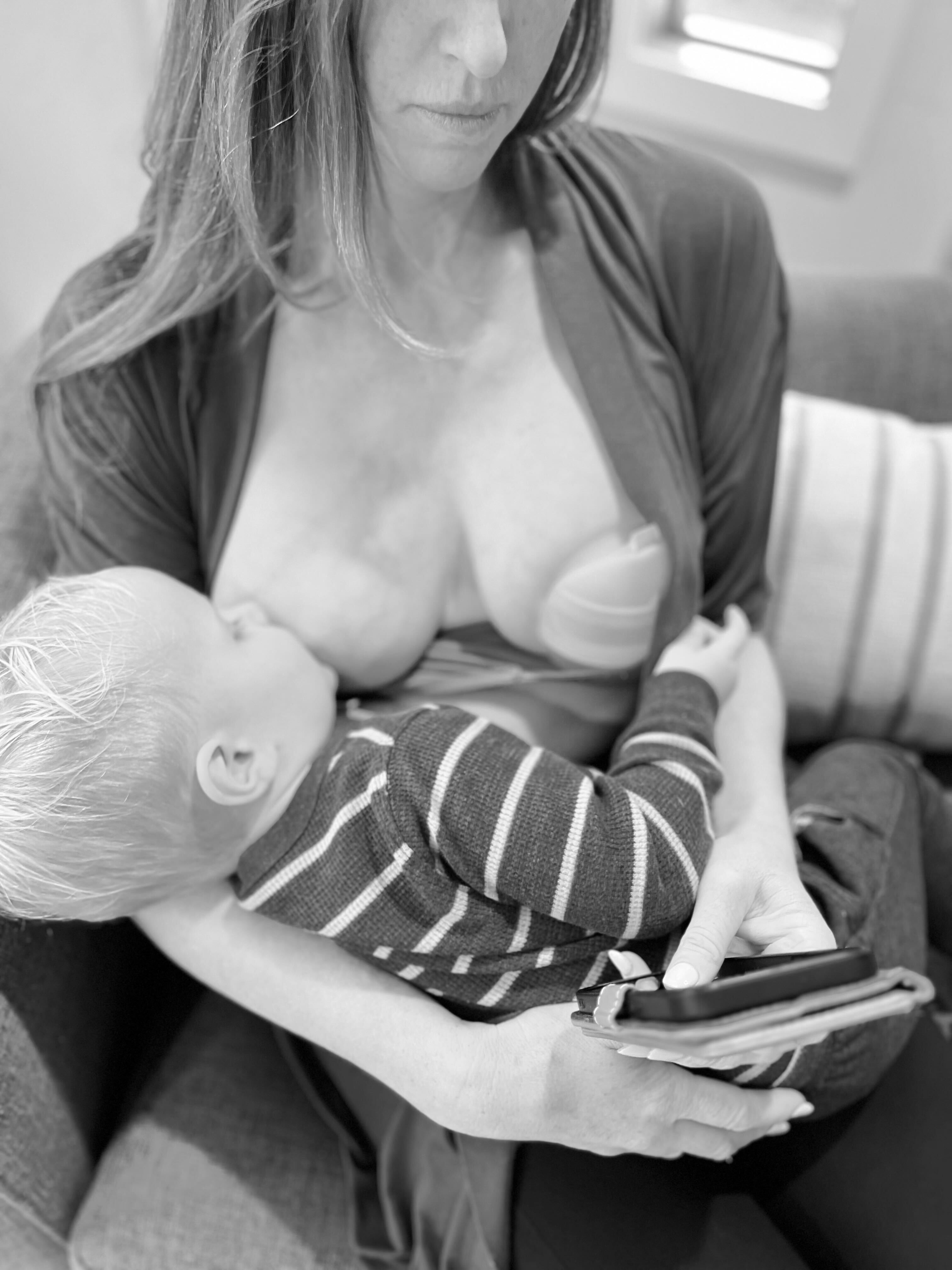 Woman using Elara hand pump while breastfeeding for swollen breasts